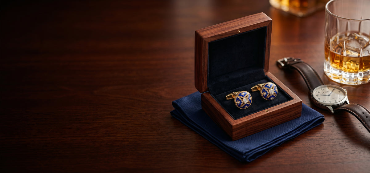 Blue and gold cufflinks displayed in a wooden gift box beside a watch